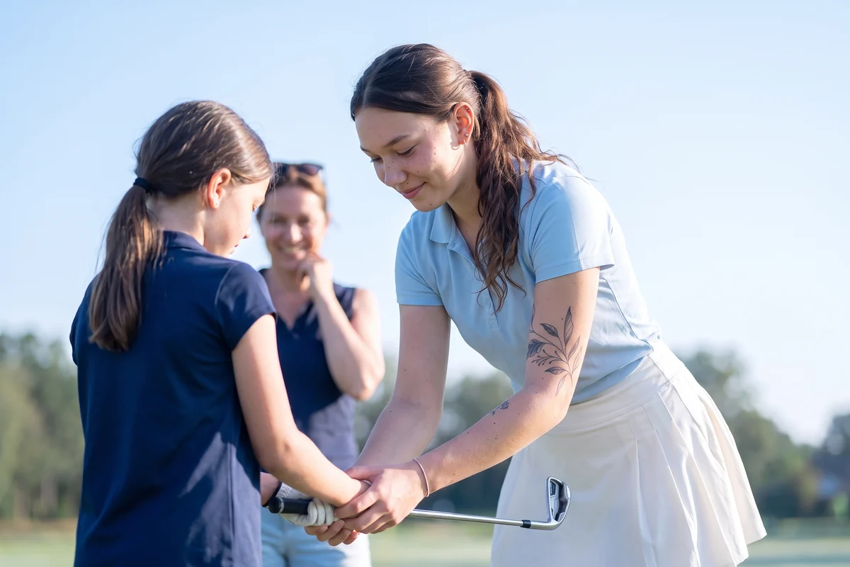 Lili Brecken guiding a junior golfer through a swing